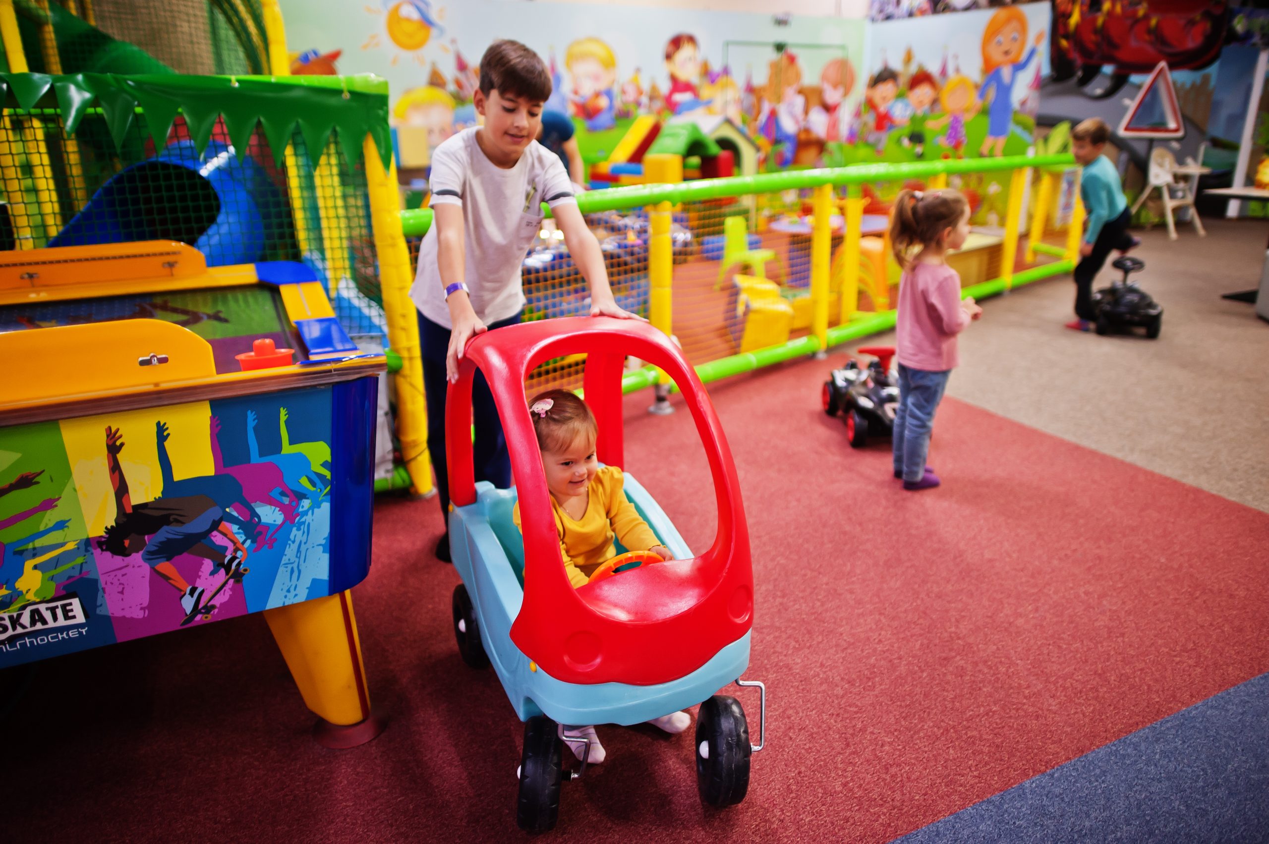 four kids playing indoor play center kindergarten preschool play room riding toy car scaled